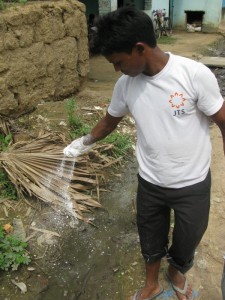 A Sujata Academy teacher spraying disinfectant along the waterway